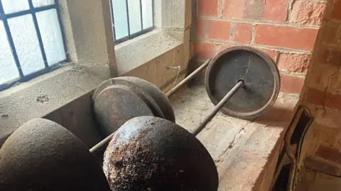 Elizabeth Baines/BBC Two metal weights sit on a window ledge