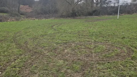 Denaby Main Junior FC Tyre tracks from off-road bikes performing 'doughnuts' on a football pitch 
