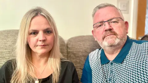 Mark Norman/BBC Tanya Linehan and her father Phil sitting on a sofa at home 