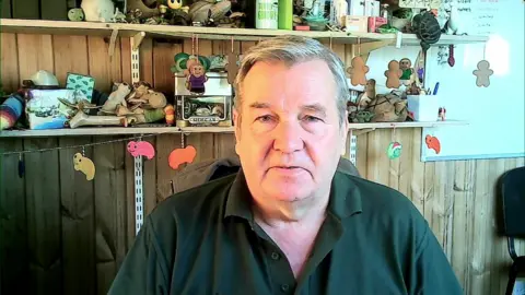 Chris Newman, a man wearing a dark green polo shirt open at the neck