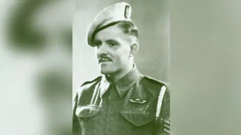 Special Air Service Regimental Association John Almonds pictured during World War Two in his Army uniform, including sergeant stripes and SAS beret. He has a short moustache and has dark hair.