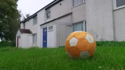 An orange football sits on grass outside homes in Catterick Garrison. 