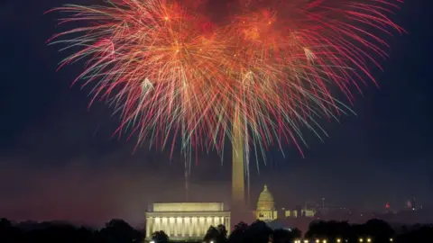 Fireworks erupt over the Washington, DC skyline at night.