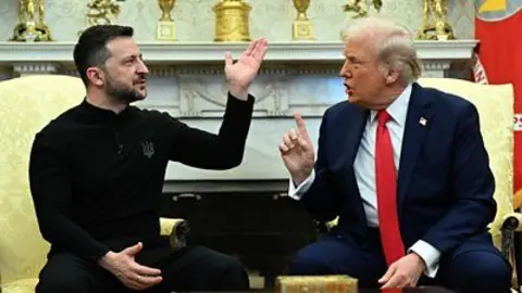 Zelensky in black, sitting on gold chair in front of gold trophies, holds up hand and faces Trump, who also sits on a gold chair and who has his forefinger raised while speaking