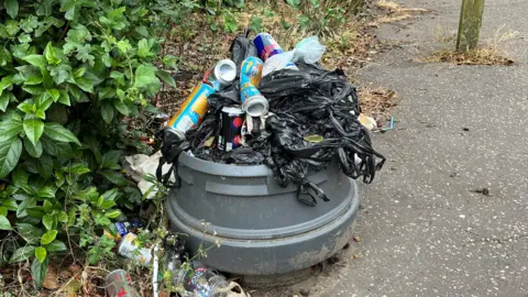 Jo Thewlis/ BBC Rubbish stacked on a broken bin