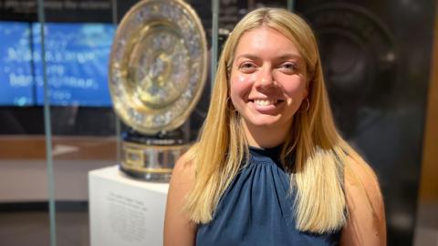 Eleanor stands in front of Wimbledon trophy at the Wimbledon Lawn Tennis Museum

