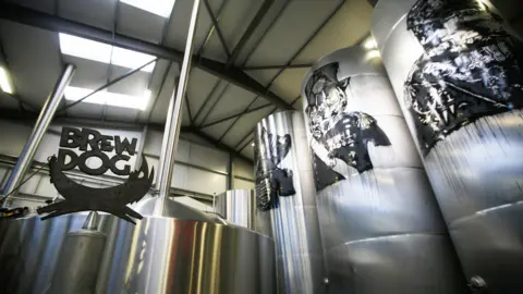 Getty Images A metalwork sculpture of the Brewdog logo stands next to silver tanks inside the firm's brewery and headquarters in Aberdeenshire in 2015.