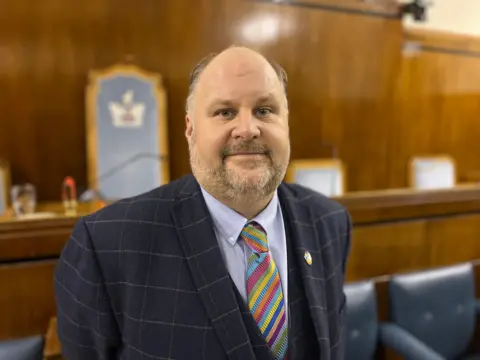 Leader of Swindon Borough Council, Jim Robbins, wearing a three piece suit and a multi-coloured tie