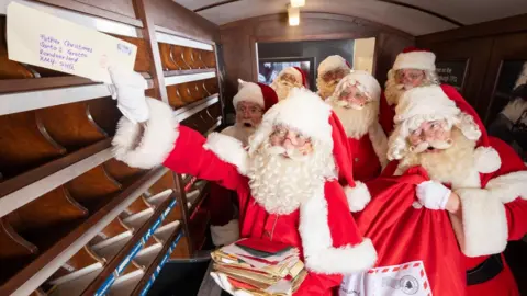 Men dressed as Father Christmas post letters