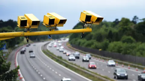 Yellow ANPR cameras on a mast above a motorway