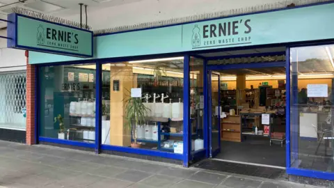 A shop with a sign saying Ernie's Zero Waste Shop above the door in black on turquoise