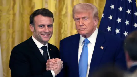 Trump and Macron hold each others hands.