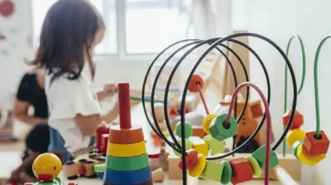 Child playing in a nursery with toys in foreground