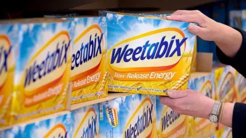 Getty Images Shelves of yellow Weetabix boxes, with the name in blue lettering and the slogan "slow release energy" below. A hand is taking one of their boxes out of the picture to the right.