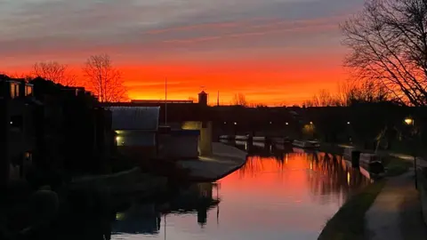CAMKINGFISHER/WEATHERWATCHERS An orange sunrise over a canal in Cambridgeshire. 