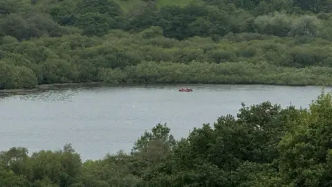 A boat is pictured on a lake in the distance