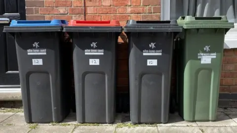 Four Milton Keynes Council wheelie bins lined up