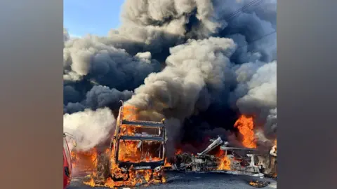 Essex County Fire and Rescue Service A double-decker bus engulfed in flames, with smoke billowing from it.