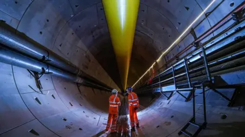 Getty Images Two workmen wearing bright orange stand inside the HS2 Bromford Tunnel 