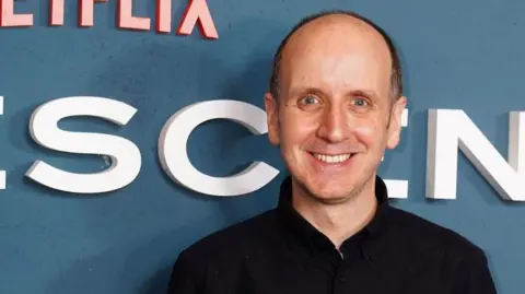 Jack Thorne wearing a black top and looking at the camera, smiling