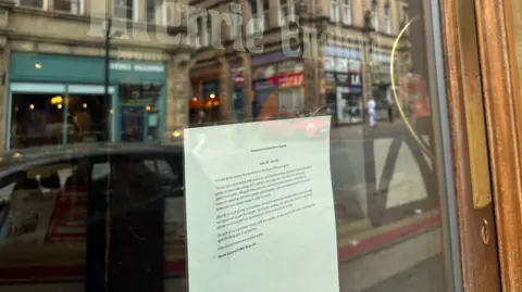 The exterior of a glass door with a poster on the glass.
