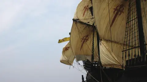 The reproduction sailing ship Nao Victoria in full sail at sea. With its cream sails billowing.