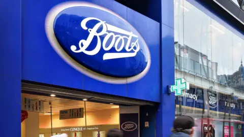 Getty Images The entrance of a large Boots store with pedestrians walking in from of the large glass store. The blue Boots signage hangs above the door. 