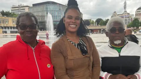Three people smiling with mirror pool in Bradford behind them