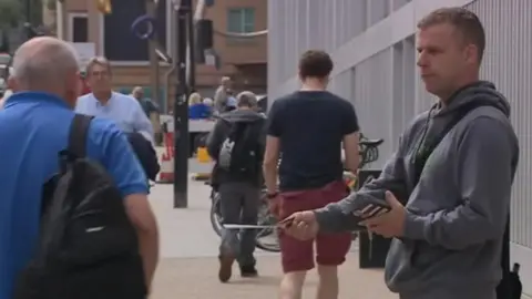 Allyn Condon wearing a grey jumper handing out leaflets outside the Bristol Royal Infirmary in Bristol