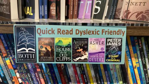 A book shelf with a sign on saying it is has a selection of dyslexic friendly books