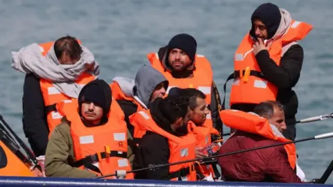 Migrants wearing orange life vests on a boat