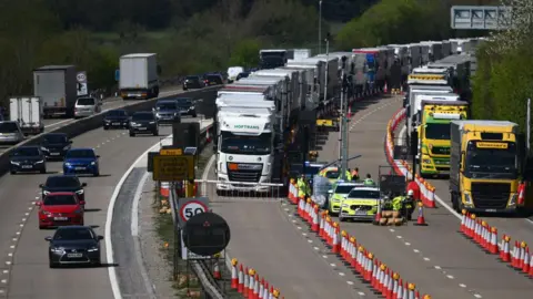 Cars and lorries on the M20 with rows of red cones between each lane. 