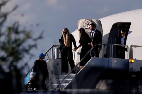 Getty Images Usha Vance is hand in hand with Erika Kirk, both dressed in black, as they disembark from Air Force Two plane in Arizona with JD Vance behind them