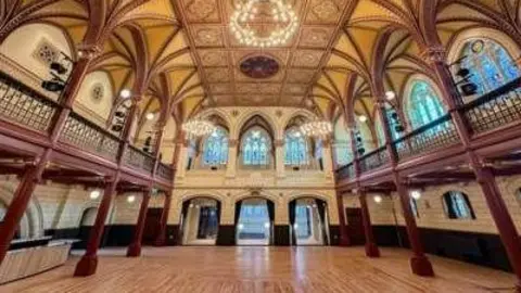 The interior of the Maison Dieu Hall in Dover, with polished floorboards, chandeliers and high oak roofbeams and pillars.