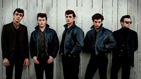Ellis Murphy as Paul McCartney, Patrick Gilmore as Pete Best, Rhys Mannion as John Lennon, Harvey Brett as George Harrison, Louis Landau as Stu Sutcliffe. All five are dressed in black trousers and black jackets - three of them leather.