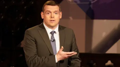 PA Media Douglas Ross in a suit at a podium