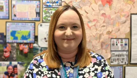 School teacher Rebecca Laird standing in front of a school notice board 