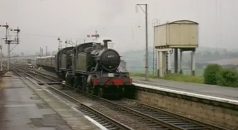 An archive image of an old train pulling into a station during a time when the railway line was active.