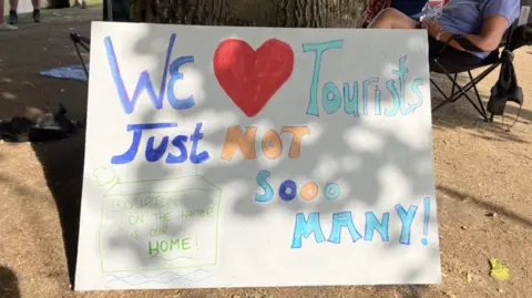 A handmade poster saying "We love tourists, just not so many."