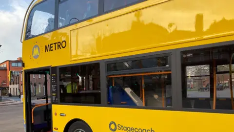 Image shows a yellow bus with the branding 'Metro' on the side