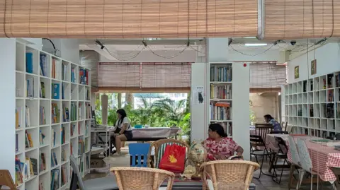 Kelly Ng/BBC A community library in Singapore featuring more than 7,000 books, and tables, chairs and other furniture donated by residents.