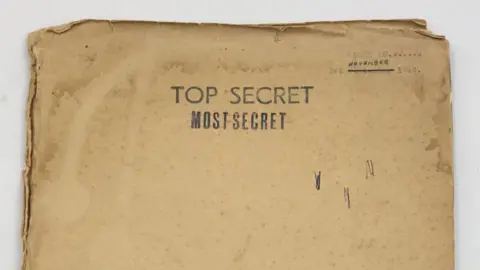 Hansons Auctioneers An old manila envelope that is stained and bent at the corners. In typed lettering, it reads: 1 November 1944. Top Secret. Most Secret.