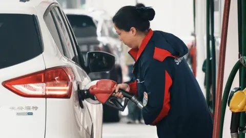 A staff member refuels vehicles at a Sinopec gas station in Hangzhou City, Zhejiang Province, China on 23 March, 2026