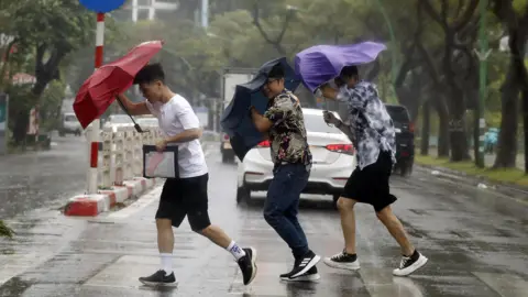 EPA People hold umbrellas as they cross a street in the rain in Hanoi, Vietnam, September 7, 2024