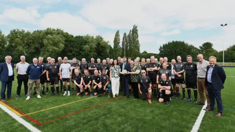 East Riding of Yorkshire Council A number of people in football kits and some in suits stand and crouch on the new pitch and look at the camera
