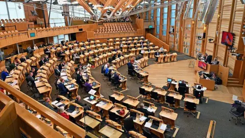 Getty Images Dozens of MSPs in their seats inside the Holyrood chamber