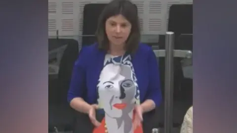 Councillor Sam Murray wearing a dress with an image of Margaret Thatcher's face on it. 