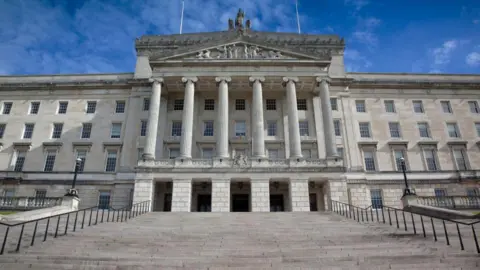 Getty Images The exterior of Stormont buildings. The photo is taken from the front of the building which is cream stone with pillars and engravements.