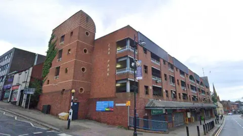 A red-brick multi-storey car park on a cloudy day.