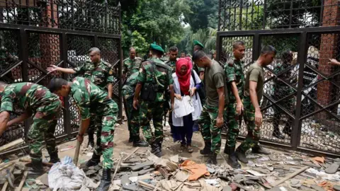 Reuters Army members clear the entrance to Ganabhaban, the Bangladesh prime minister's residence, a day after Prime Minister Sheikh Hasina resigned, in Dhaka, Bangladesh, August 6, 2024.